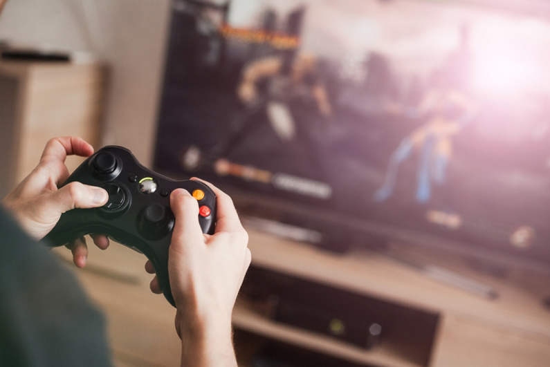 Male holding a controller while playing a video game.