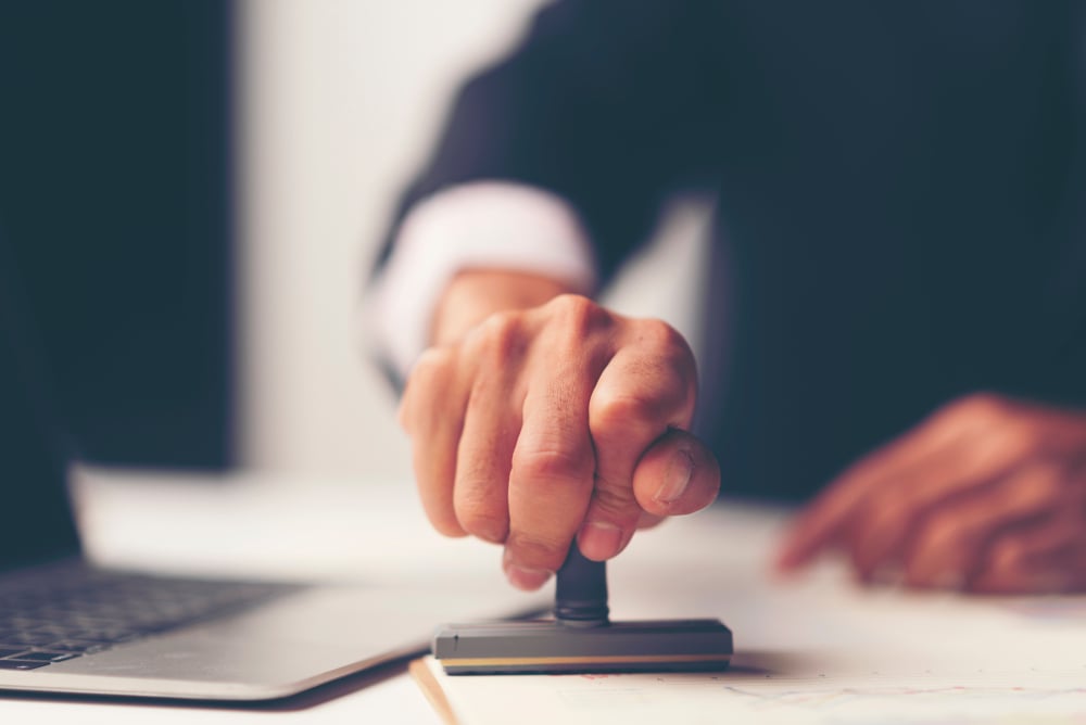 man in suit putting stamp on document